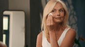 Mature woman applying skincare product to her face, reflecting routine post-treatment care to maintain the effects of Dermalax fillers
