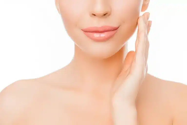 A close-up image shows a woman's lower face and neck. She has smooth, clear skin and is gently touching her cheek with one hand. Her lips are slightly smiling, and the background is plain and white.