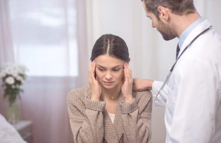 a woman suffering from migraine being examined by a docto