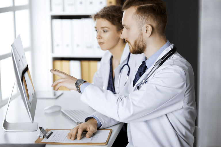 Two medical professionals reviewing Juvederm product information on a computer, illustrating the process of ordering dermal fillers online.