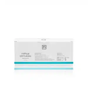 A white NITHYA STIMULATE box with "Natural Youth" written below the name. The box contains two 5.5ml serum bottles. The side of the box lists ingredients and product information. There is a minimalist design with teal accents.