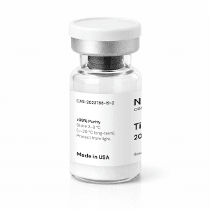A clear vial with a silver cap contains Tirzepatide 20mg as a white powder. The white label lists chemical details, storage instructions, “≥99% Purity,” and “Made in USA.”.